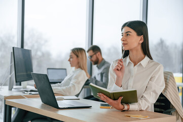 Woman is holding notepad. Successful team are working together in the office. Conception of business