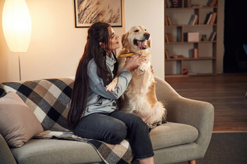 Obraz na płótnie Canvas Sitting on the sofa. Woman is with golden retriever dog at home