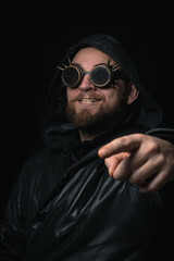 A man in a hood, wearing vintage steampunk goggles looking at the camera close-up
