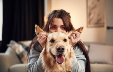 Close up view, portrait. Woman is with golden retriever dog at home