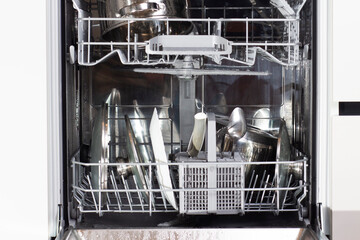 Cutlery and plates after washer in the dishwasher. 
Clean dishes in dishwasher machine after washing cycle.