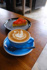 Berry cake and blue mug of cappuccino with latte art