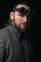 charismatic man in a classic suit and steampunk goggles on a black background stylish Portrait