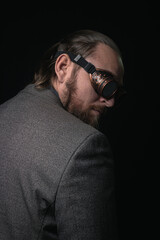 Fototapeta premium charismatic man in a classic suit and steampunk goggles on a black background stylish Portrait