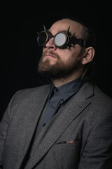 charismatic man in a classic suit and steampunk goggles on a black background stylish Portrait