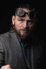 charismatic man in a classic suit and steampunk goggles on a black background stylish Portrait