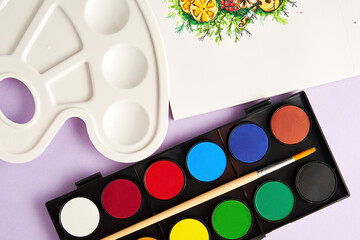 Top view of new paints, brush, palette and a picture on a white canvas. Leisure activity and hobby....
