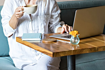 Woman with a cup of coffee working at laptop face unrecognized