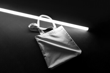 Tote Bag branding mockup template on a black foam background with neon light lamp and deep shadows,...