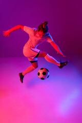 Fototapeta na wymiar Dribbling. Young professional female football, soccer player in motion, training, playing over gradient pink background in neon light