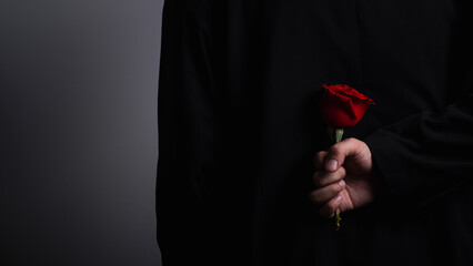 man hand wearing suite with red rose flower on background. holidays card with copy space valentine celebration concept.