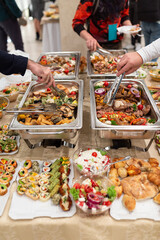 Close up of hands scooping food. Buffet catering meal concept.