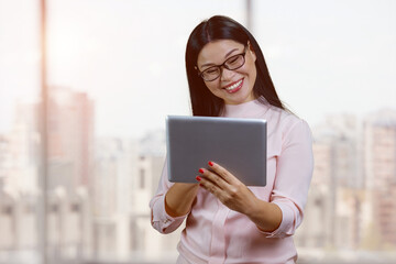 Fototapeta premium Portrait of smiling young asian businesswoman with glasses. Indoor windows bacgkground.