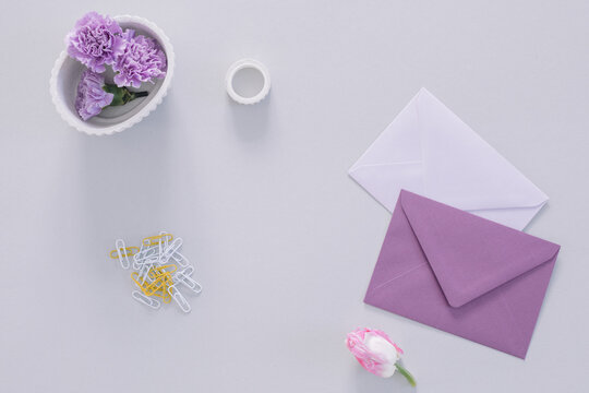Overhead view of purple carnation flower heads, envelopes and assorted stationery on a table