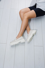 Women shoes. Close up of female legs in leather white loafers. New spring-summer collection of...