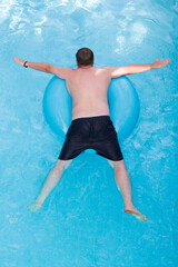 A man floats on inflatable circle, top view.
