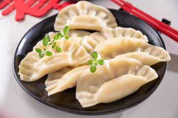 Dim sum. Homemade Chinese dumplings are served on a black plate. They eat with chopsticks. Oriental cuisine, light snacks for a traditional lunch. . High quality photo. 