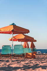 Blue sun loungers and orange umbrellas on a deserted beach in Crete