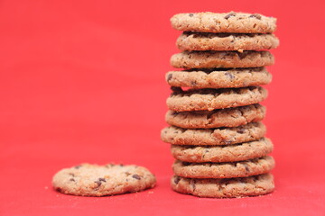 A stack of delicious oatmeal cookies with cereal on a red background.