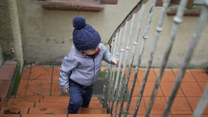 Toddler boy going up the stairs. Baby child goes up the stair during winter season