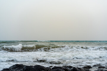 Rough sea with cloudy sky in the evening light at the beach with lava rocks from Fuerteventura with copy space 