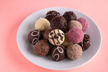 photo round chocolate candies lying in a pile on a white round plate