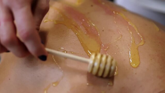 close up of a person holding a spoon of honey