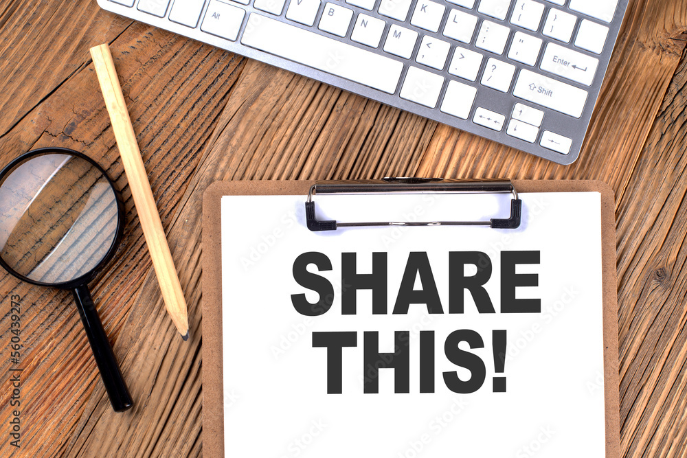Aufkleber share this text on paper clipboard with magnifier and keyboard on wooden background