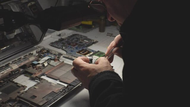 an adult man in a workshop repairs a laptop. close-up. High-quality shooting in 4k format