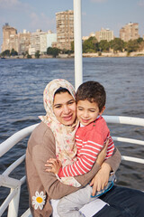 Fototapeta na wymiar Happy mother with adorable son resting on a big yacht sailing in Nile, Cairo, Egypt. 