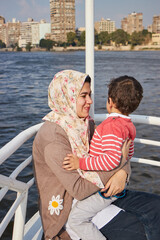 Happy mother with adorable son resting on a big yacht sailing in Nile, Cairo, Egypt. 