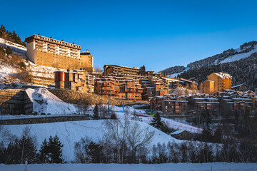 Sunset light illuminating Soldeu town ski slopes and snow capped mountains. Ski winter holidays in...
