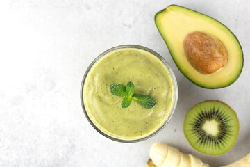 Avocado smoothie on a gray background, top view. Green smoothie with avocado, kiwi and banana, Copy space. 