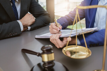 Business people and lawyers discussing contract papers with brass scale on wooden desk in office. Law, legal services, advice, Justice concept