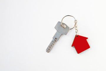 Key and house shaped keychain arrangement on red background. Top view, flat lay. Real estate,...