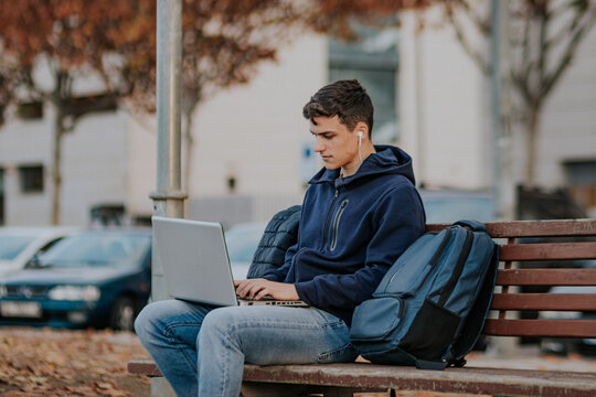 Concentrated Man Browsing Laptop On Bench