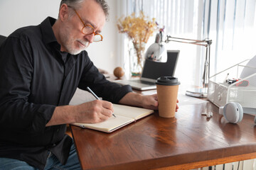 Focused freelancer writing in organizer at home office desk