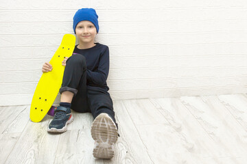 boy in a hat sits on the floor near the wall with a skateboard in his hands, active lifestyle © Елена Белоусова