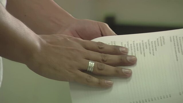 Hands of a Male Teacher Turning Pages of a School Textbook during Economics Lesson. Close Up.