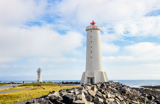 Akranes lighthouses on the west coast of Iceland. Bigger lighthouse is operational and smaller is deactivated old one. White building by the sea on sunny beautiful day.