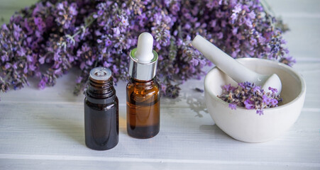 Fototapeta na wymiar A bottle of essential oil with fresh blooming lavender twigs