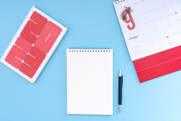 Vacation, trip or holiday planning concept - Public Holiday calendar with passport, notepad, pen, earphone and tablet on blue background. Top view flat lay copy space.