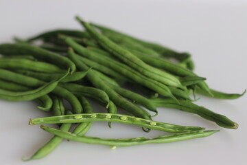 Bunch of French Beans shot on white back ground with few sliced half. It is also called green beans, bush beans, string beans, snap beans, haricot vert