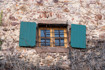 Old castle window with green shutters and old brickwork