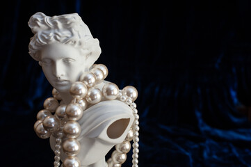 sculpture of apollo in pearl beads on dark blue velvet. close up. copy space. 