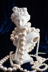 sculpture of apollo in pearl beads on dark blue velvet. close up
