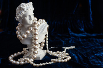 sculpture of apollo in pearl beads on dark blue velvet. copy space. art concept