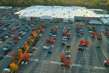 Aerial view of large parking lot in front of rgocery store with many parked colorful cars. Carpark...