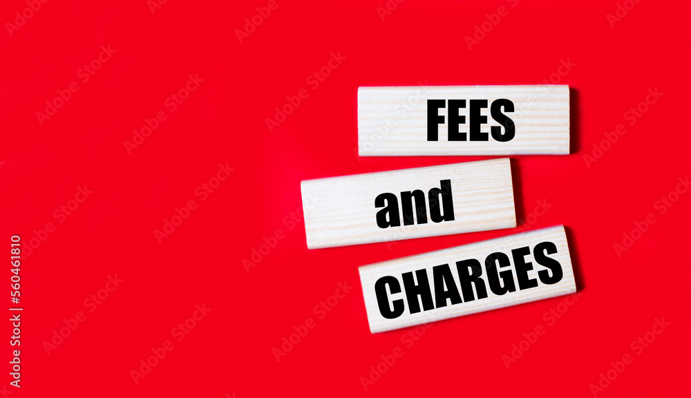 Aufkleber three wooden blocks with the text fees and charges on a bright red background. copy space