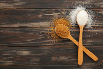 Fototapeta na wymiar White and brown sugar in wood spoon on brown background.